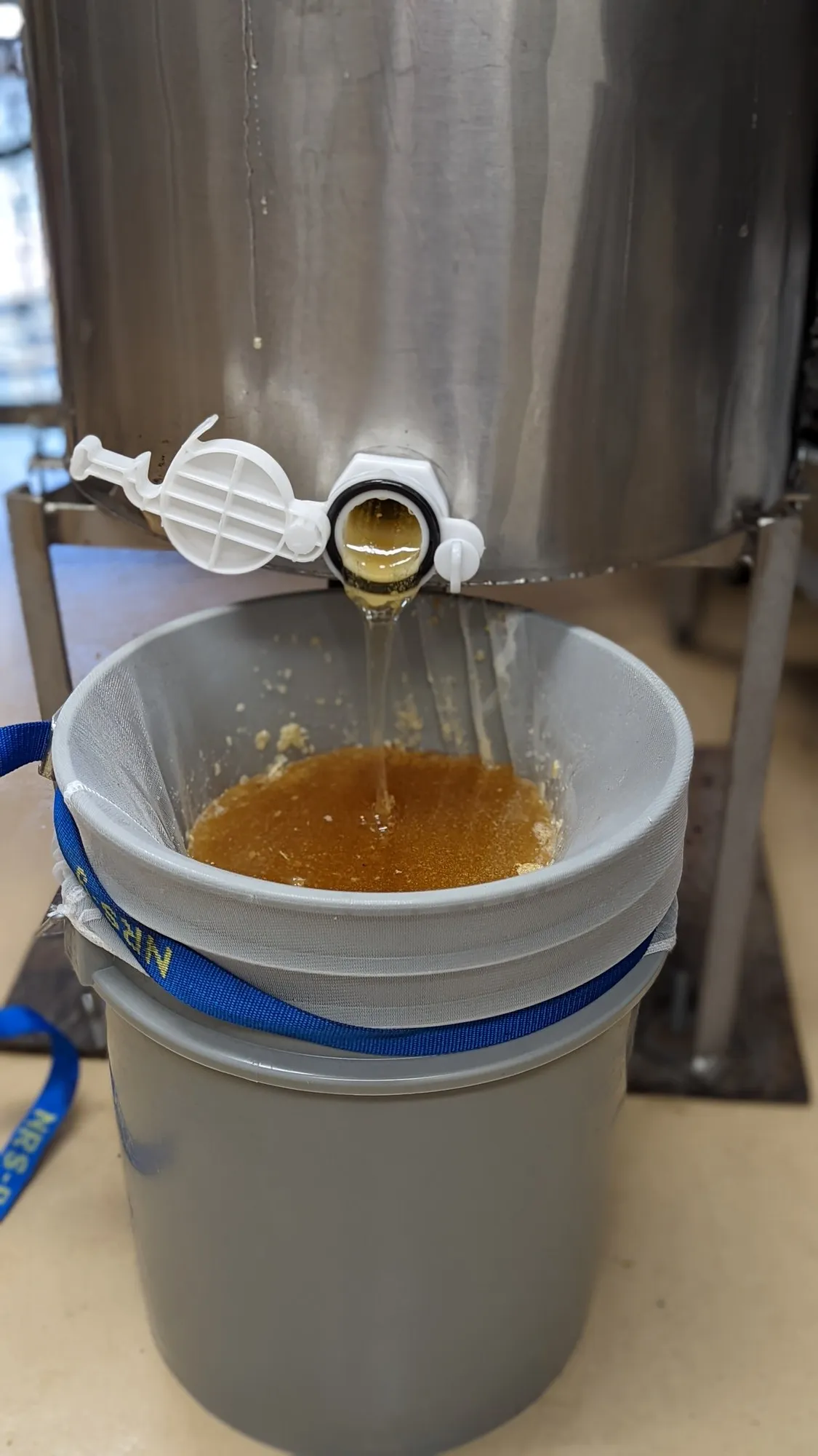 Raw honey being poured into a pail