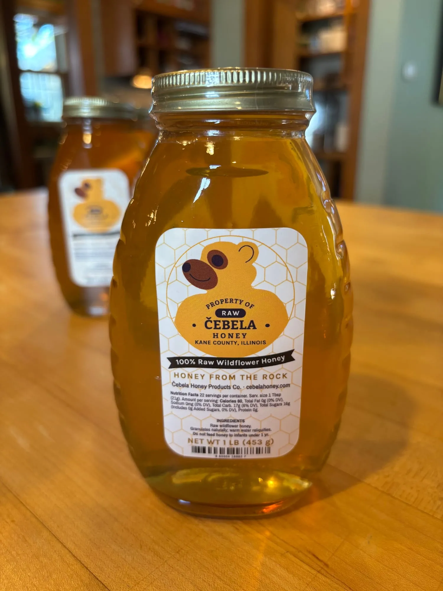 A one-pound jar of Čebela raw wildflower honey with our label applied